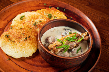 Hearty meal of crispy fritters, tender meat, and creamy sauce, garnished with herbs