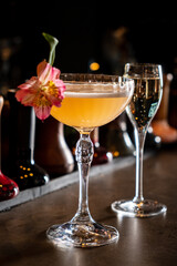 Delicious cocktail with a delicate flower garnishing awaits at a lively bar setting after sunset