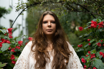young woman musician outdoors surrounded by vibrant flowers and greenery in soft natural light