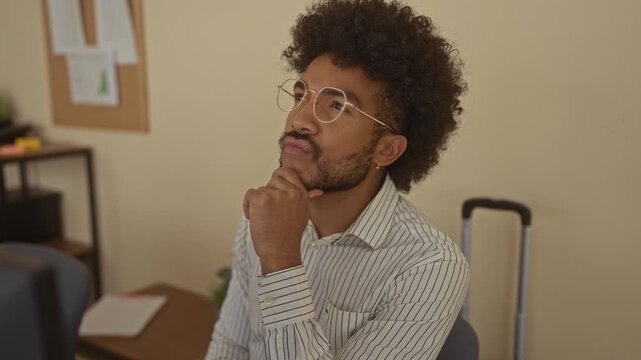 Man in an office with an idea, wearing glasses and a striped shirt, gesturing excitement in a professional indoor setting, conveying creativity and innovation.