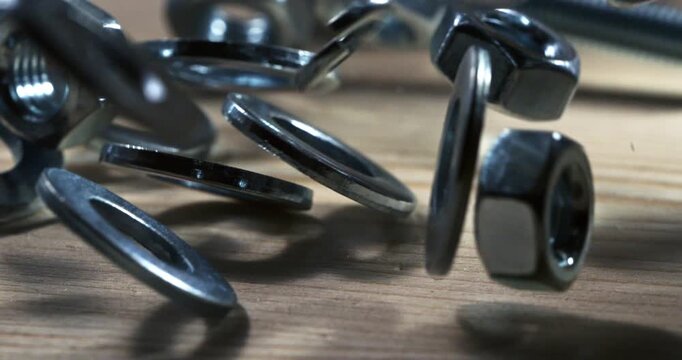 Slow Motion Macro Shot Of Metal Washers, Nuts And Bolts Scattering Across A Wooden Surface With Sharp Reflections, Industrial Texture And Precise Mechanical Motion At 1000 Fps. Concept Of Engineering 