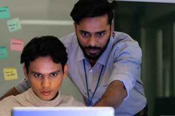 Business team analyzing data on laptops with growth chart in background. Diverse professionals collaborating in office, discussing financial performance, strategy, and success analytics in workplace.