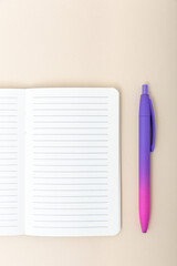 Open notebook with gradient pen on beige background. Concept of planning, organization and creativity. Vertical photo