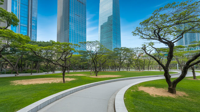 A daytime urban park scene with modern glass skyscrapers in the background.