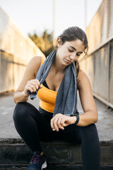 Woman checking fitness tracker after urban running workout