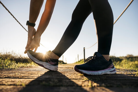 Woman prepares for a run, stretching outdoors at sunrise