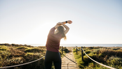 Woman stretching arms on beach path preparing for workout