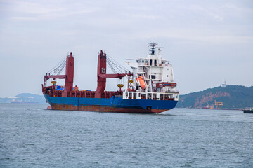 Fototapeta premium Large General Cargo Vessel with Cranes Moving Through Seascape,Cargo Ship Sailing on the Ocean