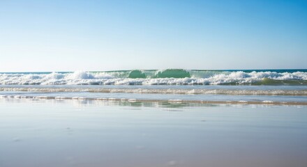 Obraz premium Serene Ocean Waves Breaking on a Wet Sandy Beach Under a Clear Blue Sky