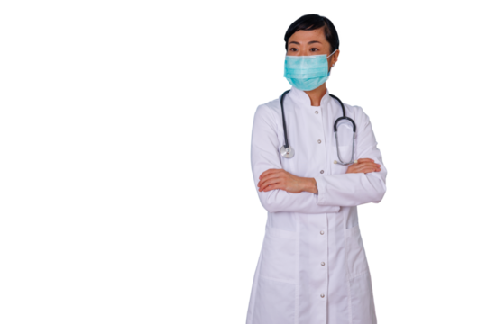 Asian doctor woman wearing a surgical mask and white lab coat, arms crossed, looking away. Professional healthcare worker