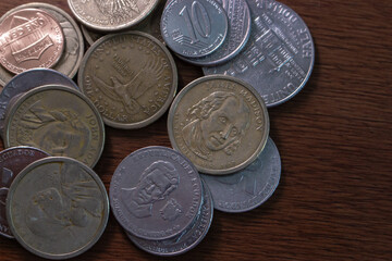 Close-up of assorted coins from the United States and Ecuador, including commemorative and standard currency on a wooden table.