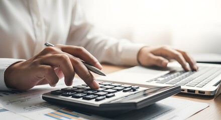 Financial concept Closeup of a person using a calculator and laptop for financial calculations and accounting tasks