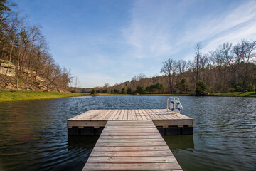 Naklejka premium Wooden Dock Extending Into Calm Pond