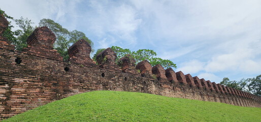 A brick wall over a dirt embankment and boundary stone of temple used to block gun path in past....