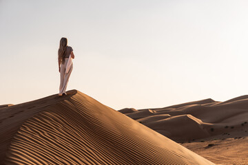 Woman exploring desert sand dunes in oman in sunset