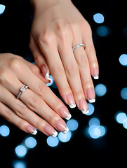 Close-up of female hands with stylish manicure against festive bokeh lights. Detailed nail design, glossy polish and elegant hand pose for beauty category.