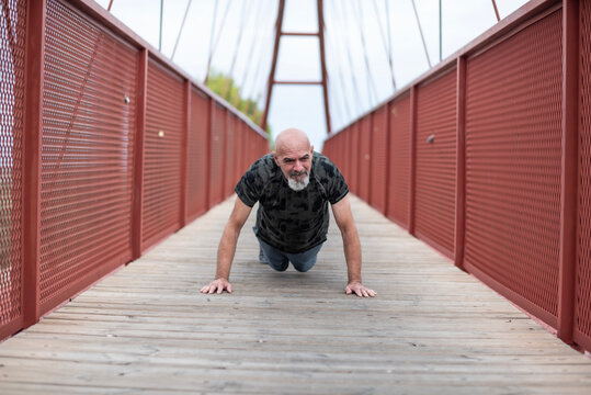 A 65-year-old man does push-ups after going for a run on top of a pedestrian bridge