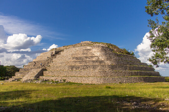 Wide view of the Kinich Kakm&oacute; Pyramid in Izamal, Yucat&aacute;n, showing its massive stepped Mayan architecture, ancient stone terraces, archaeological landscape, historic pre-Hispanic heritage, and tourists
