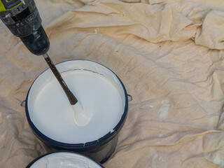 Mixing paint with cordless drill and paddle mixer for painting walls