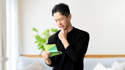 通帳を見て考える男性