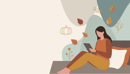 Cozy autumn relaxation Woman using digital tablet in bed with fall leaves background