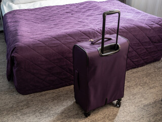 purple suitcase and purple bedspread on double bed