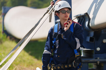 Engineers in safety gear conduct a detailed inspection of wind turbine blades at a construction site. Large blades are placed on the ground, highlighting the renewable energy technology.