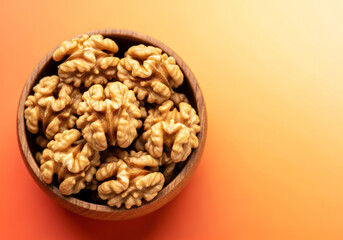 Walnut kernel halves in a wooden bowl closeup from above on colored background healthy eating walnut concept super foods with copy space