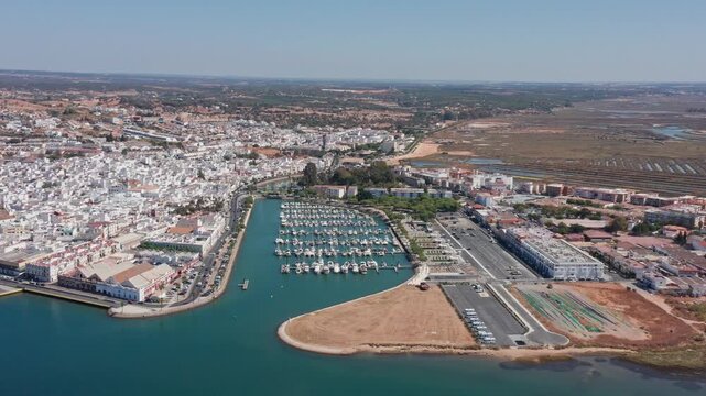 Aerial view drone shot of Ayamonte Aerial view marina and waterfront yachts clustered in curved harbor basin, marina breakwater, quay promenades and parking area near white town.