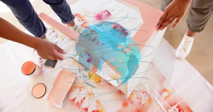 Woman dipping roller and rolling paint for craft panel as partner holding panel blue globe shifting