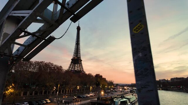 Unique low-angle perspective of the Eiffel Tower at dusk, artfully framed by a stark industrial bridge structure, contrasting iconic beauty with raw urban elements.