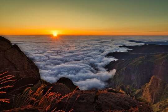 A beautiful sunset over a mountain range with a thick layer of clouds - Powered by Adobe