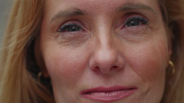 Close-up portrait of middle-aged woman with natural expression looking into camera, showing fine details of skin texture, eye makeup, and subtle emotion in her gaze