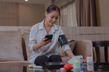 A woman is checking her blood pressure in the lounge.