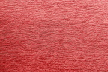 Close-up of a textured metal surface with a vibrant reddish hue showcasing subtle lines and patterns during bright lighting conditions