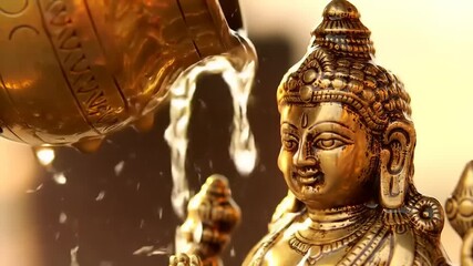 Golden deity receiving water in worship.