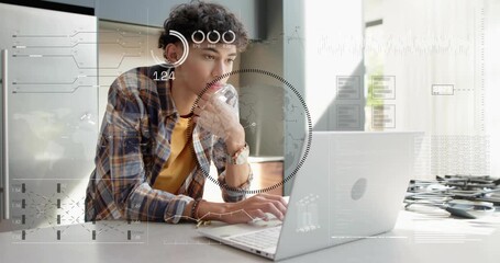 Male student focusing and typing on laptop in kitchen, HUD overlays appearing and analyzing data