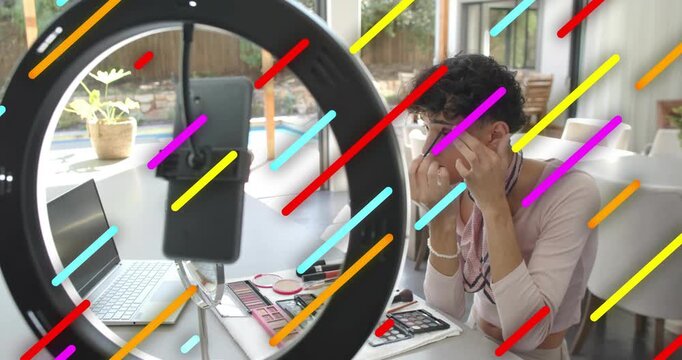 Male beauty vlogger arranging at ring light phone, doing eye makeup for tutorial, stripes showing