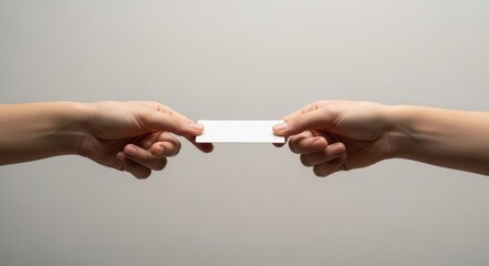 Two hands exchanging a blank white rectangular business card against a simple, neutral gray background.