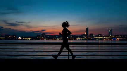 Silhouette of female runner jogging at sunrise city skyline waterfront motivational fitness lifestyle