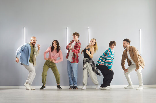 Group of diverse young adults posing playfully in modern dance studio. Happy energetic people in casual clothes practicing hip hop choreography and enjoying fun urban dance while training together. - Powered by Adobe