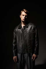 Stylish young man showcases modern masculinity in a striking dark setting