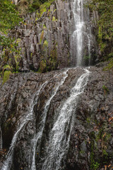 Rugged waterfall streams down dark stone, creating a powerful cascade
