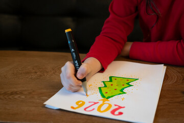 A girl draws a Christmas tree with a marker. High quality photo
