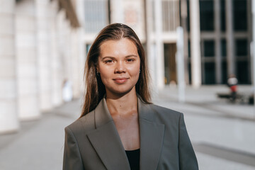 Professional woman confidently standing with a folder, expressing determination and poise amidst contemporary architecture.