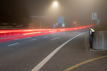 Street with light trails at a foggy night.