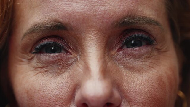 Extreme close-up of middle-aged woman&rsquo;s eyes showing gentle expression and natural warmth, fine details of skin and makeup emphasizing age and authenticity