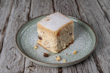 snack with delicious pie with sweet cottage cheese and raisins on a light green ceramic plate on a...