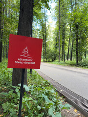 Public park with sign warning of steep descent. The risk of falling and injury during descent. The dangers of poor terrain and injury prevention. Keeping people safe while walking uses warning signs