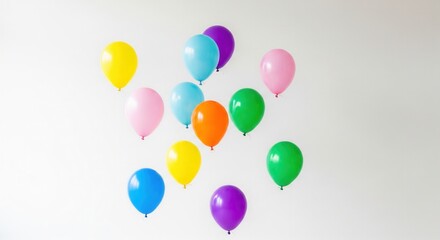 A dozen colorful balloons float against a plain white wall. This cheerful and festive scene evokes joy and celebration, perfect for party invitations, birthday greetings, or event decor.